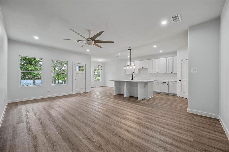 Unfurnished living room with ceiling fan and light wood-type flooring