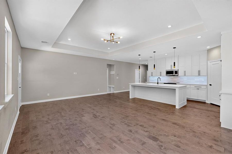 Living room featuring a raised ceiling, a chandelier, dark wood finished floors, and recessed lighting Living room featuring a raised ceiling, a chandelier, dark wood finished floors, and recessed lighting