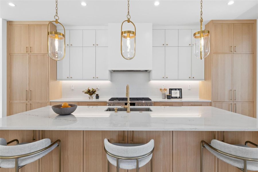 Kitchen featuring a kitchen breakfast bar, light stone counters, hanging light fixtures, and dual tone cabinets