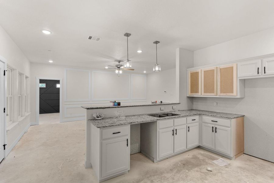 Kitchen featuring a peninsula, light stone counters, a ceiling fan, white cabinets, and recessed lighting Kitchen featuring a peninsula, light stone counters, a ceiling fan, white cabinets, and recessed lighting