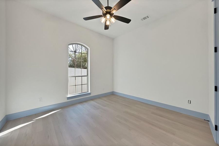 Empty room featuring light wood-type flooring and a ceiling fan