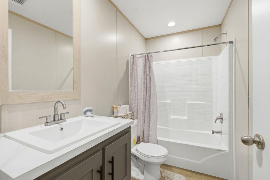 Bathroom with vanity, shower / bathtub combination with curtain, and ornamental molding