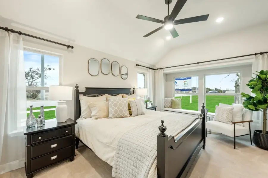 Bedroom with dark wood four-poster bed, vaulted ceiling, ceiling fan, and large windows with outdoor views