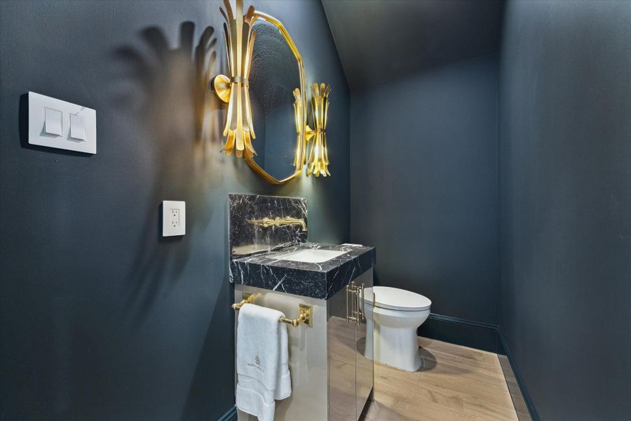 First floor powder features Nero Marquina Marble Countertop, designer light fixtures, Kallista plumbing, and is color-drenched with Sherwin Williams Mount Etna to create a statement space.