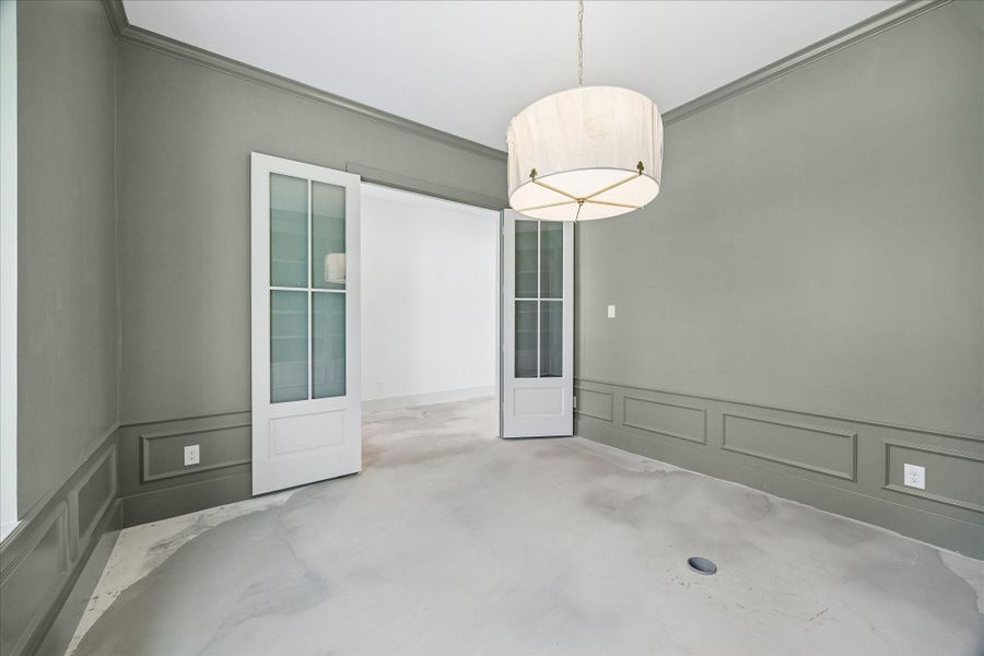 Alternate view of the dedicated study highlights the refined millwork, soft neutral tones, and elegant designer lighting that define the space. Glass paneled double doors provide both privacy and connection to the main living areas, making this room ideal for a home office or quiet retreat. Thoughtful architectural details and a calm, sophisticated palette create a functional workspace with timeless appeal.