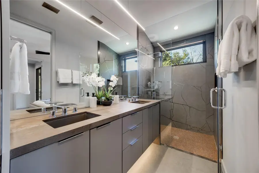 Full bathroom featuring double vanity, curated stone work, and luxury finishes