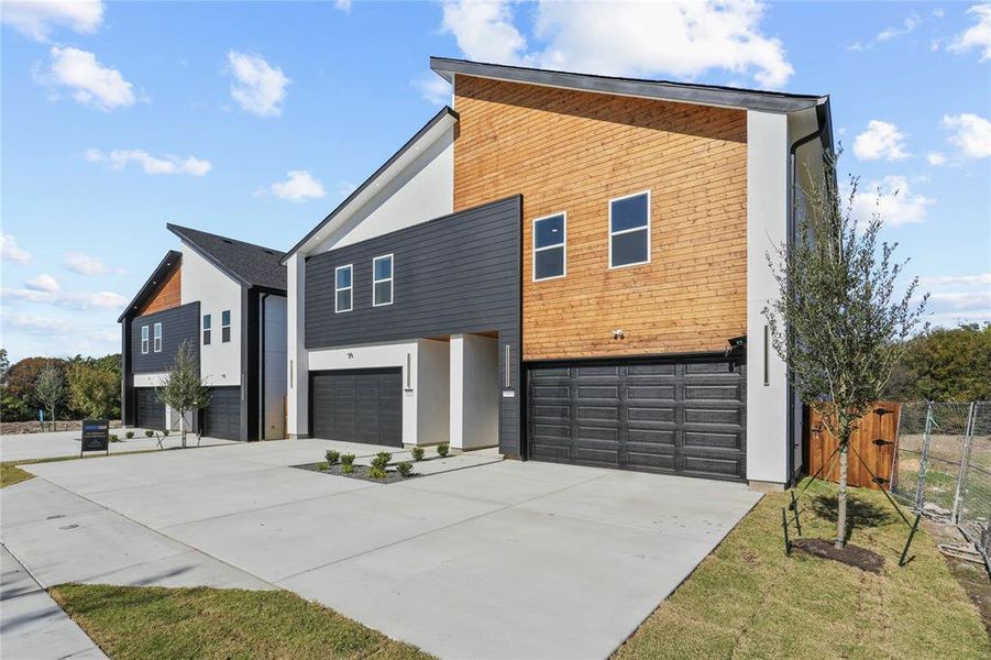 View of front of house with an attached garage, concrete driveway, and stucco siding