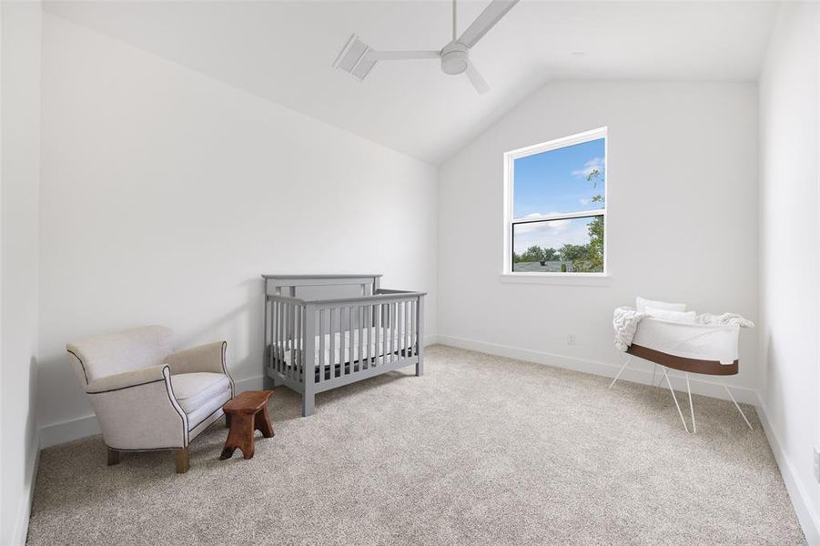 Bedroom featuring vaulted ceiling, carpet floors, ceiling fan, and a crib Bedroom featuring vaulted ceiling, carpet floors, ceiling fan, and a crib
