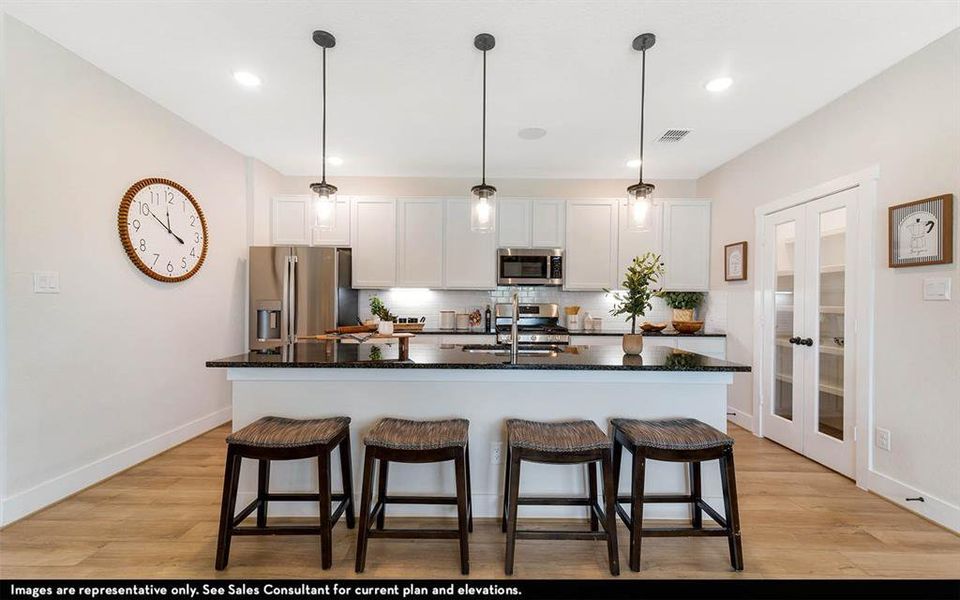 Kitchen featuring an island with pendant lighting, white cabinetry, dark countertops, and stainless steel appliances