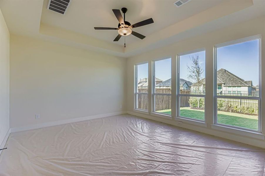 Unfurnished room featuring a tray ceiling, a ceiling fan, and a residential view