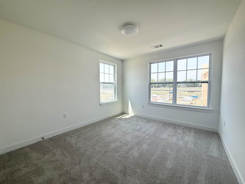 Carpeted spare room featuring baseboards