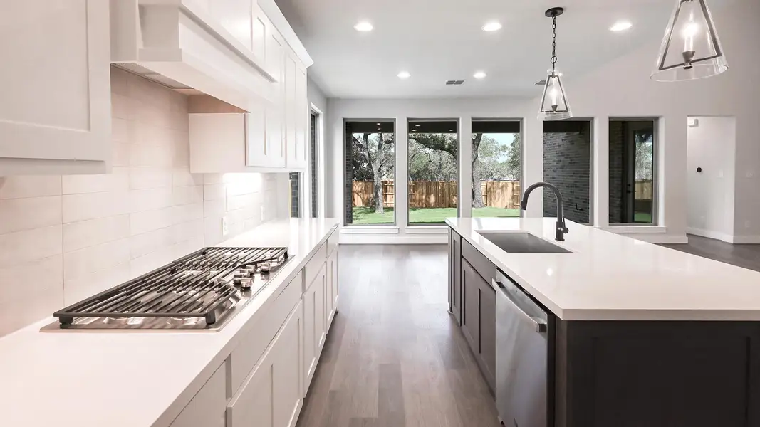 Kitchen with dark wood finished floors, light countertops, backsplash, appliances with stainless steel finishes, and recessed lighting