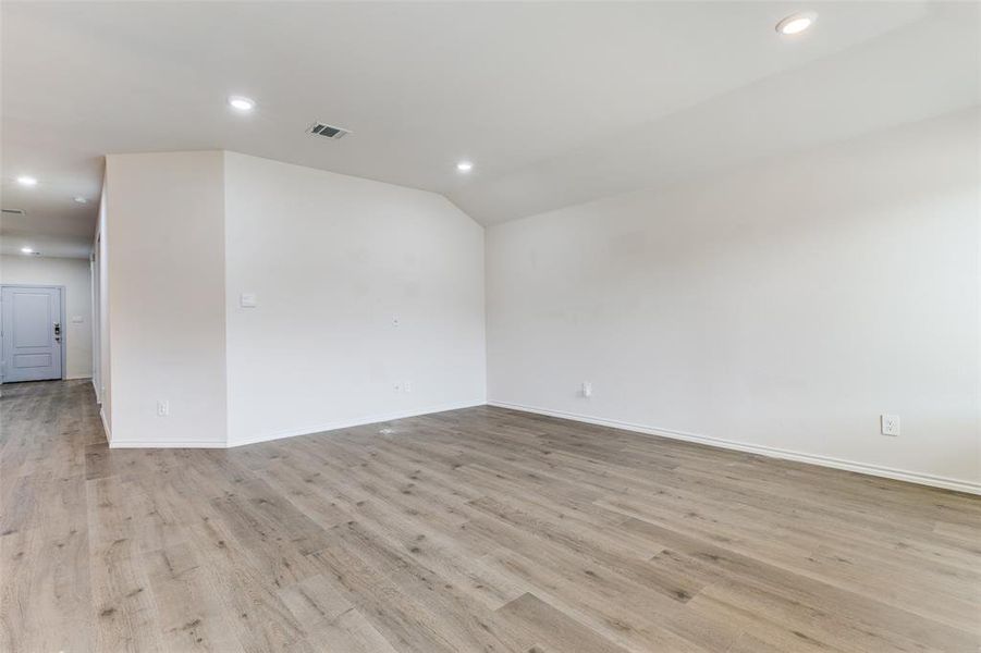 Open-concept living space featuring wood-finish flooring, recessed lighting, and crisp white walls Open-concept living space featuring wood-finish flooring, recessed lighting, and crisp white walls