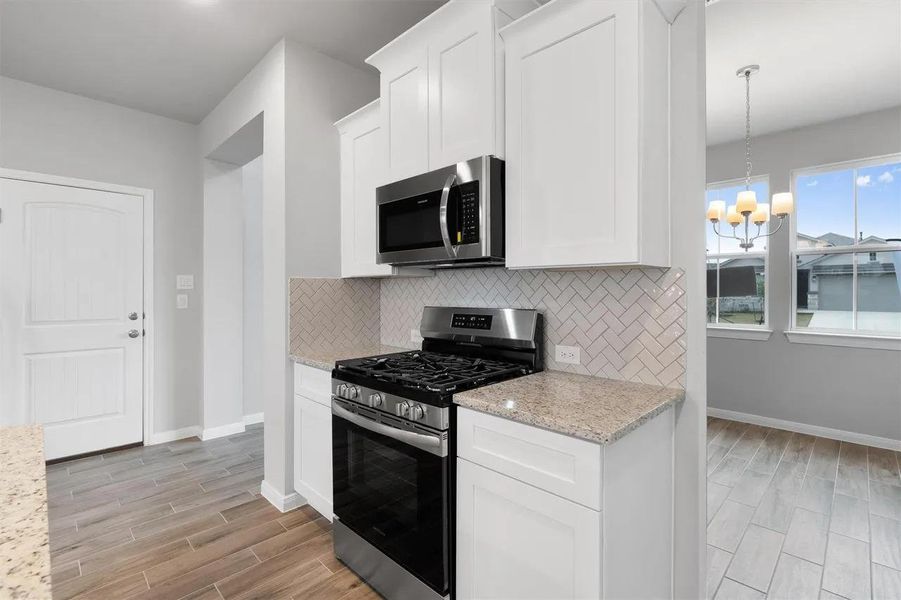 Modern kitchen with sleek stainless steel appliances and natural light from expansive windows.