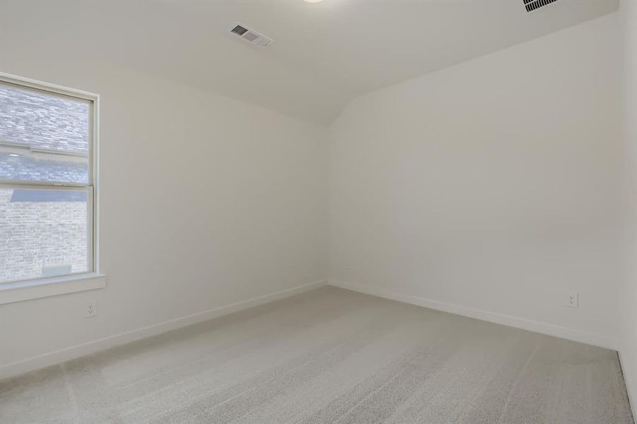 Carpeted interior room featuring a window with white trim, light-colored walls, and a sloped ceiling
