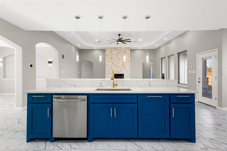 Kitchen featuring blue cabinetry, a ceiling fan, stainless steel dishwasher, and a fireplace