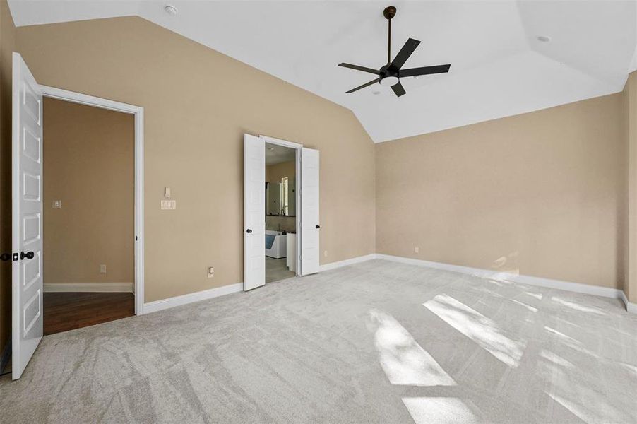 Unfurnished bedroom with lofted ceiling, carpet, ensuite bath, and ceiling fan