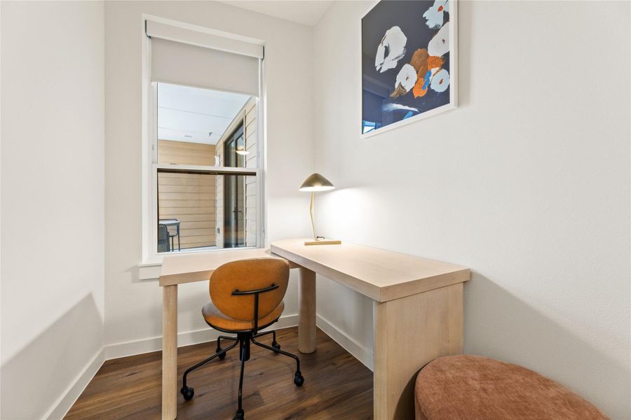 A dedicated home office nook features rich hardwood flooring and a tall window. A dedicated home office nook features rich hardwood flooring and a tall window.