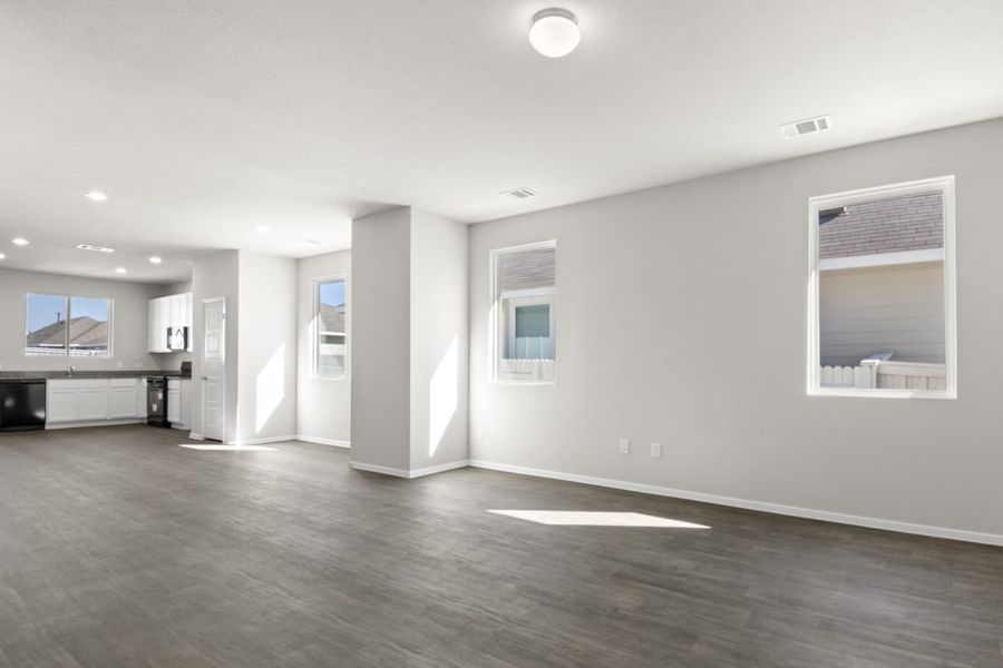 Image of a living room with light grey walls, dark brown flooring and windows