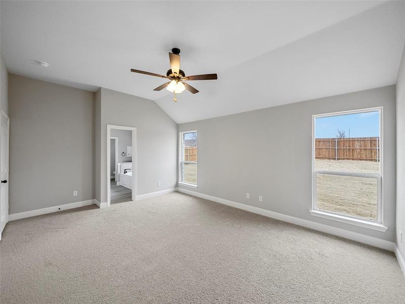 Spare room with lofted ceiling, a ceiling fan, baseboards, and carpet floors