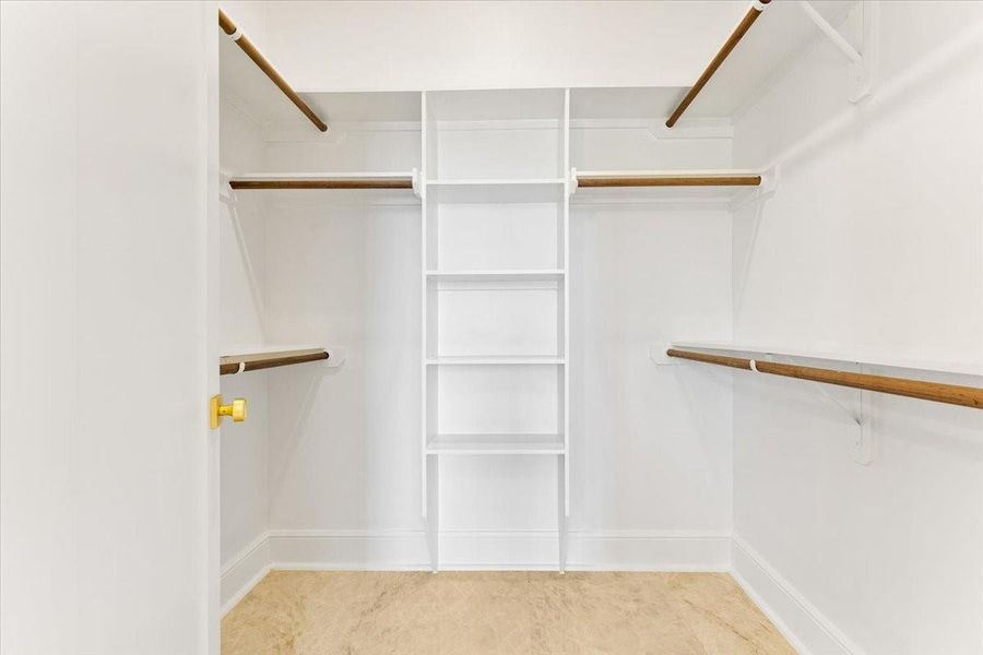 Spacious walk-in closet with built-in shelving and hanging space for optimal organization. Spacious walk-in closet with built-in shelving and hanging space for optimal organization.