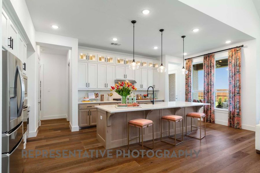 Kitchen with light countertops, a kitchen bar, stainless steel fridge, dark wood-type flooring, and an island with sink Kitchen with light countertops, a kitchen bar, stainless steel fridge, dark wood-type flooring, and an island with sink