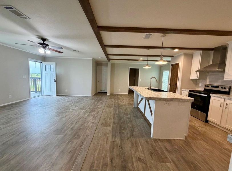 Open-concept living space featuring wood-finish flooring, exposed ceiling beams, a ceiling fan, and light gray wall paint