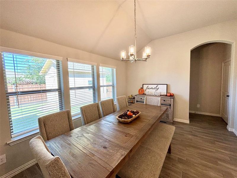 Dining area featuring arched walkways, lofted ceiling, dark wood finished floors, and a chandelier Dining area featuring arched walkways, lofted ceiling, dark wood finished floors, and a chandelier