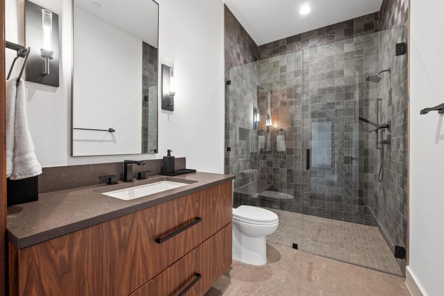 Bathroom featuring toilet, vanity, and a stall shower Bathroom featuring toilet, vanity, and a stall shower