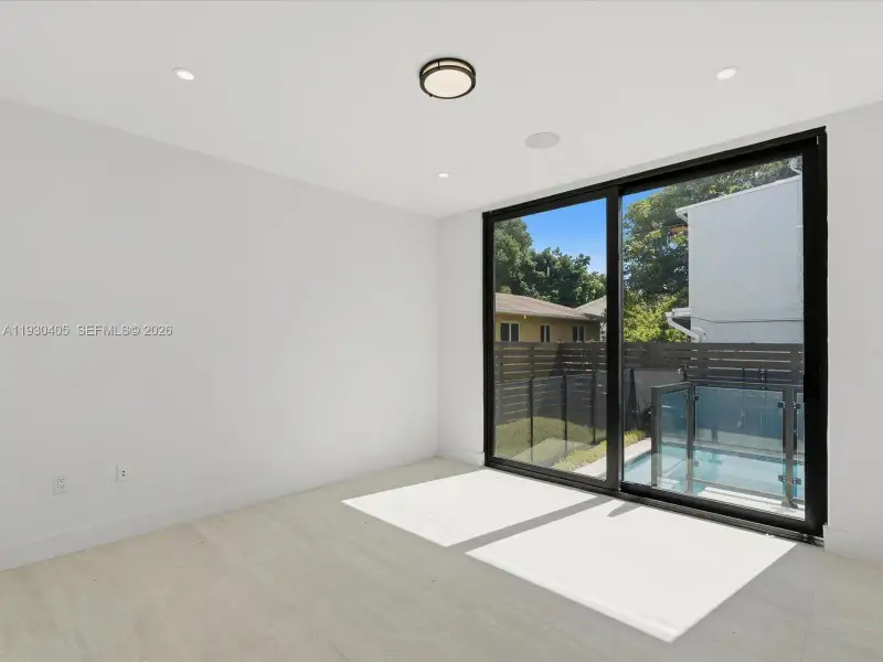 Interior space featuring wood-finish flooring, recessed lighting, a flush-mount ceiling fixture, and a floor-to-ceiling sliding glass door Interior space featuring wood-finish flooring, recessed lighting, a flush-mount ceiling fixture, and a floor-to-ceiling sliding glass door