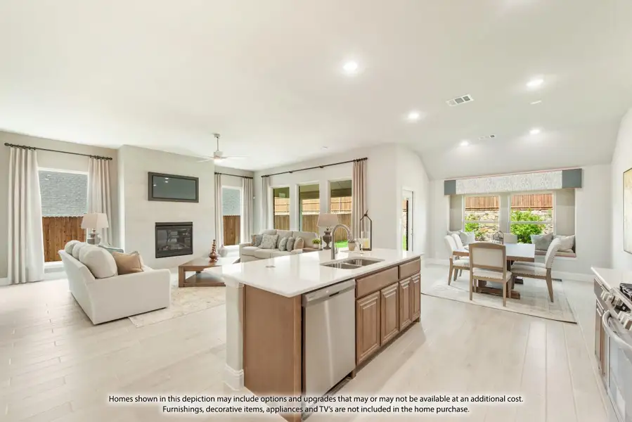 Open-concept kitchen with center island flowing into living and dining areas, light wood floors, and fireplace Open-concept kitchen with center island flowing into living and dining areas, light wood floors, and fireplace
