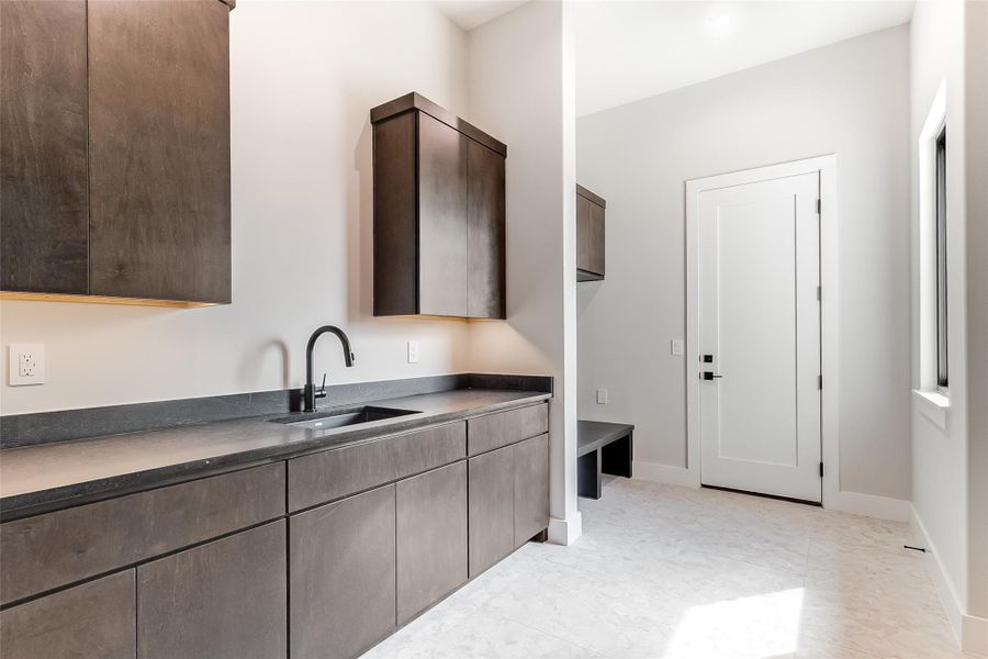Kitchen with a sink, dark brown cabinets, dark countertops, and baseboards Kitchen with a sink, dark brown cabinets, dark countertops, and baseboards