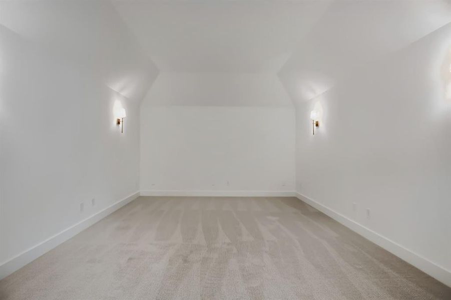 Spacious room featuring neutral carpeting, crisp white walls, and elegant sconce lighting Spacious room featuring neutral carpeting, crisp white walls, and elegant sconce lighting