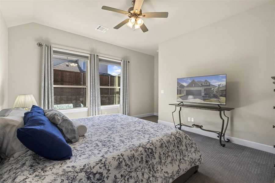 Bedroom lofted ceiling, ceiling fan, and carpet flooring