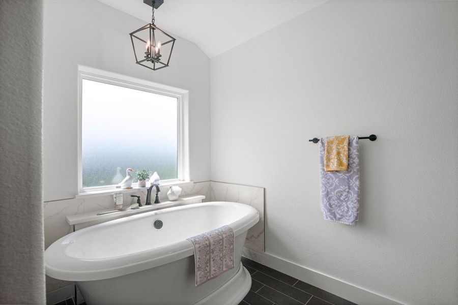 Bathroom with a freestanding bath, tile patterned floors, a chandelier, and vaulted ceiling Bathroom with a freestanding bath, tile patterned floors, a chandelier, and vaulted ceiling