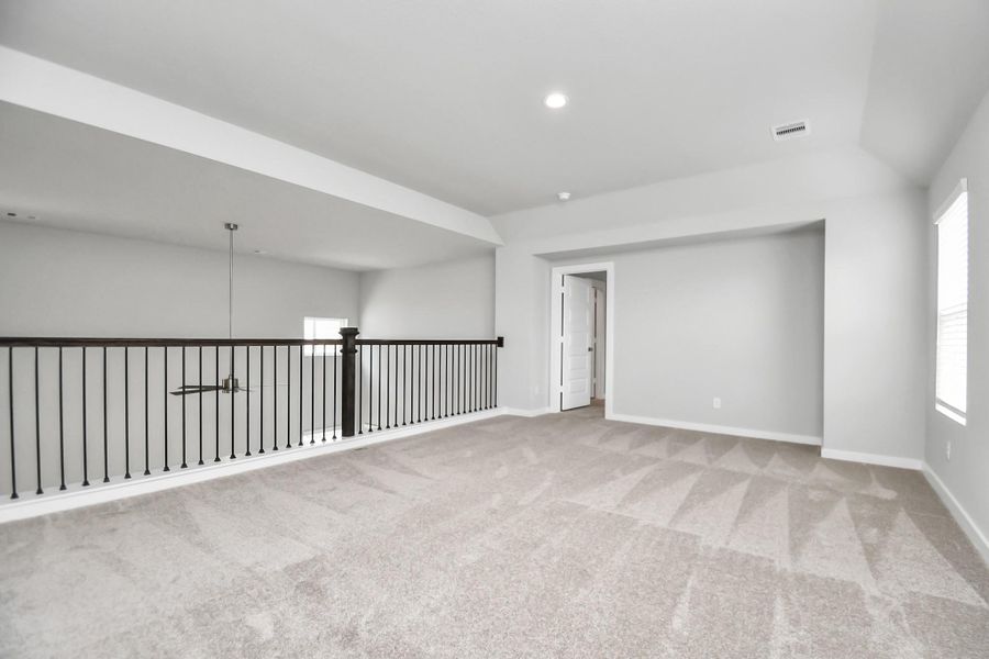 Ascend to relaxation in this fantastic game room! Ideal for both casual gatherings and adult gaming, it boasts plush carpet, lofty ceilings, custom paint, and ample windows for abundant natural light. Sample photo of completed home with similar floor plan. Actual colors and selections may vary.