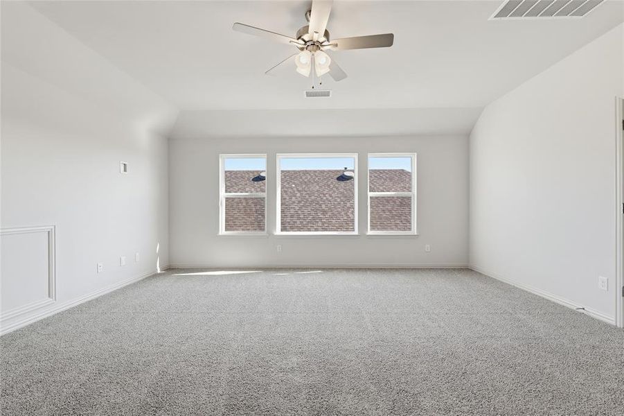 Carpeted empty room with vaulted ceiling and ceiling fan Carpeted empty room with vaulted ceiling and ceiling fan