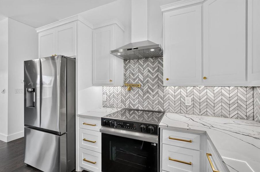 Contemporary kitchen featuring white shaker cabinetry, stainless steel appliances, and a herringbone pattern tile backsplash