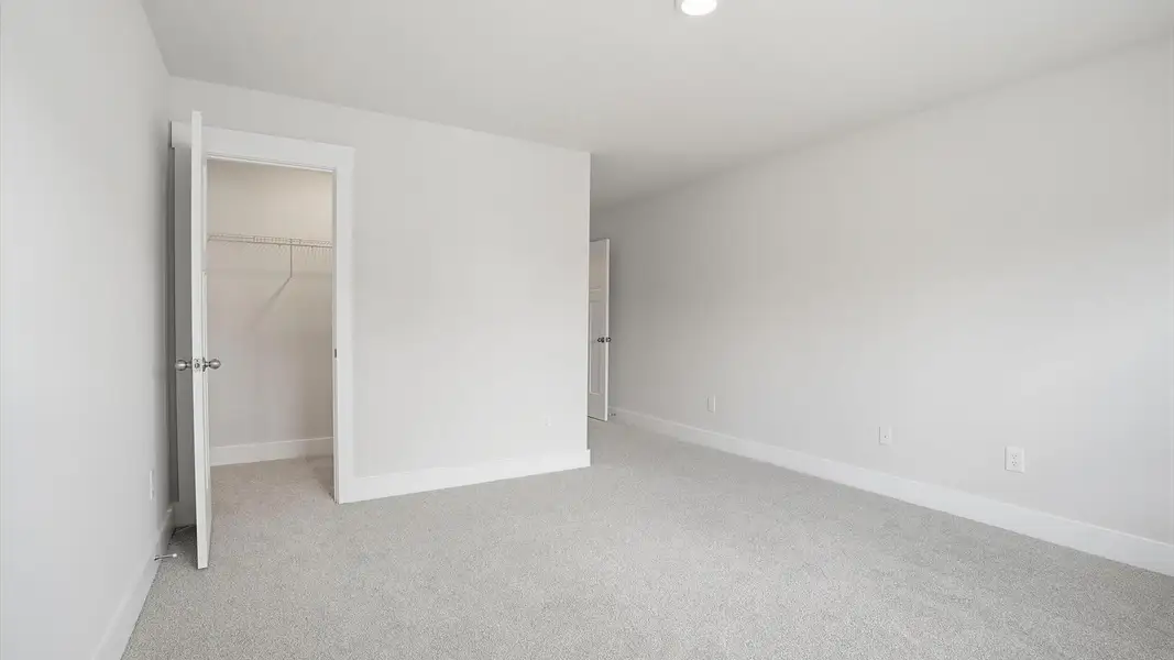 First-rate secondary bedroom with a spacious walk-in closet and elegant carpeted flooring at Village at Midway First-rate secondary bedroom with a spacious walk-in closet and elegant carpeted flooring at Village at Midway