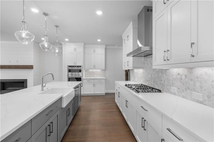 Kitchen featuring wall chimney exhaust hood, hanging light fixtures, recessed lighting, decorative backsplash, and dark wood-style floors Kitchen featuring wall chimney exhaust hood, hanging light fixtures, recessed lighting, decorative backsplash, and dark wood-style floors