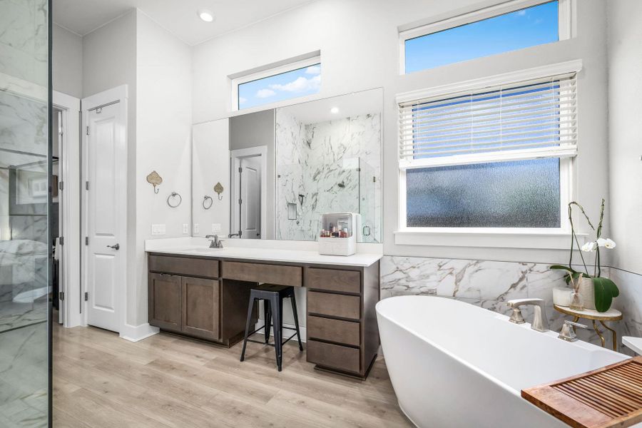 A spacious primary bathroom boasts a freestanding tub, ample vanity space, and a glass-enclosed shower with elegant marble accents.