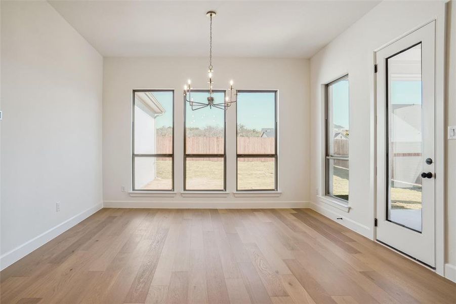 Unfurnished dining area featuring a chandelier and light hardwood / wood-style flooring