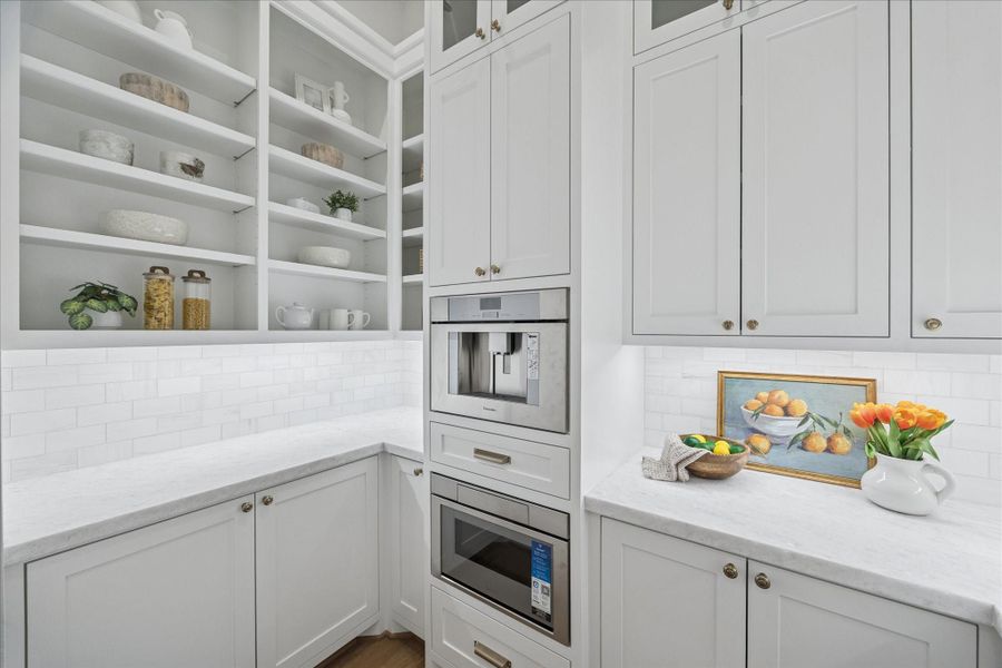 Tucked behind the main kitchen, an integrated prep zone features a panel-ready refrigerator, built-in coffee system, microwave, and extensive storage. This secondary workspace enhances entertaining efficiency while maintaining the clean, gallery-like aesthetic of the front kitchen. *Previous Project*