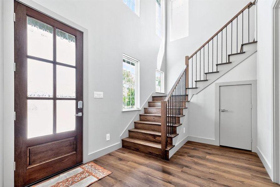 Entryway featuring healthy amount of natural light, dark wood-style floors, and a high ceiling Entryway featuring healthy amount of natural light, dark wood-style floors, and a high ceiling