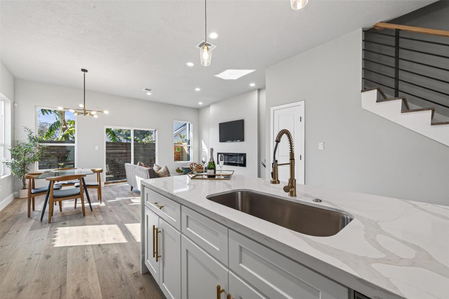 Expansive island view highlighting an undermount stainless steel sink, pull-down gooseneck faucet, built-in dishwasher, and abundant storage—designed for both everyday living and elevated entertaining.