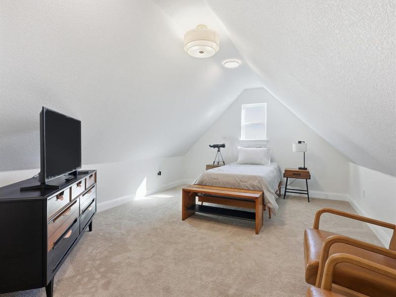 Bedroom with light carpet, lofted ceiling, and a textured ceiling