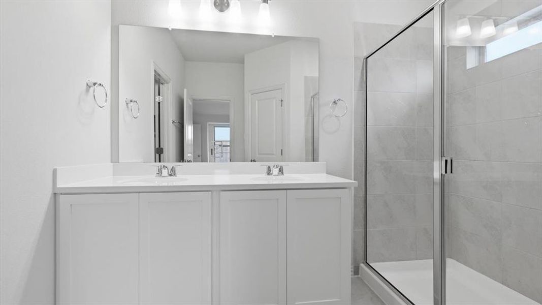 Dual vanity with white cabinetry, integrated sinks, chrome fixtures, and a large wall-mounted mirror