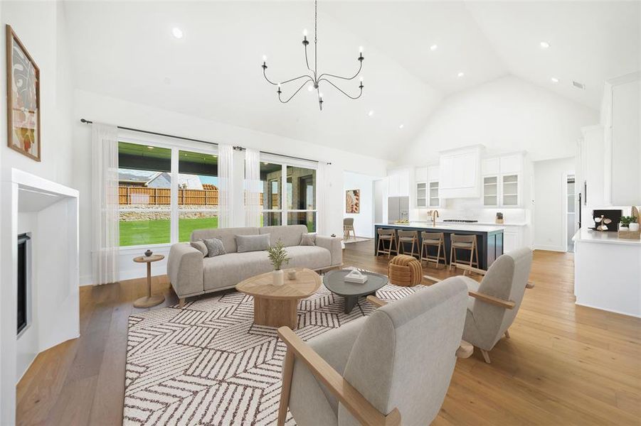 Living room featuring high vaulted ceiling, wood-type flooring, recessed lighting, a chandelier, and a fireplace