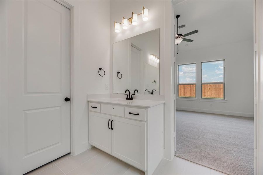 Bathroom with vanity, light tile patterned floors, and a ceiling fan Bathroom with vanity, light tile patterned floors, and a ceiling fan