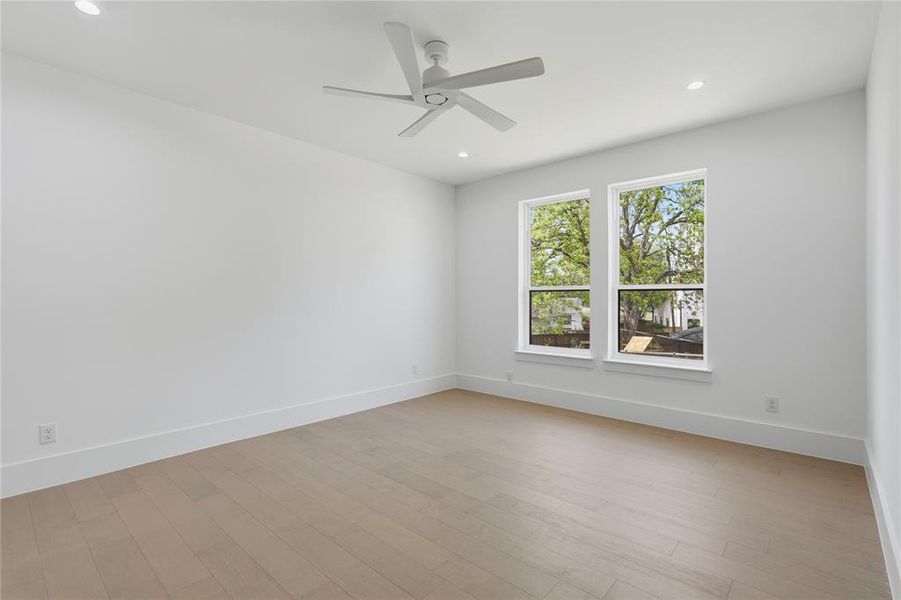 Bright room featuring light wood-finish flooring and a contemporary ceiling fan